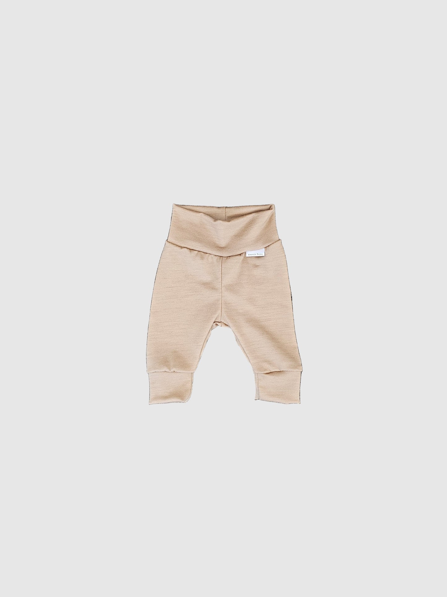 Beige baby romper on a textured gray surface