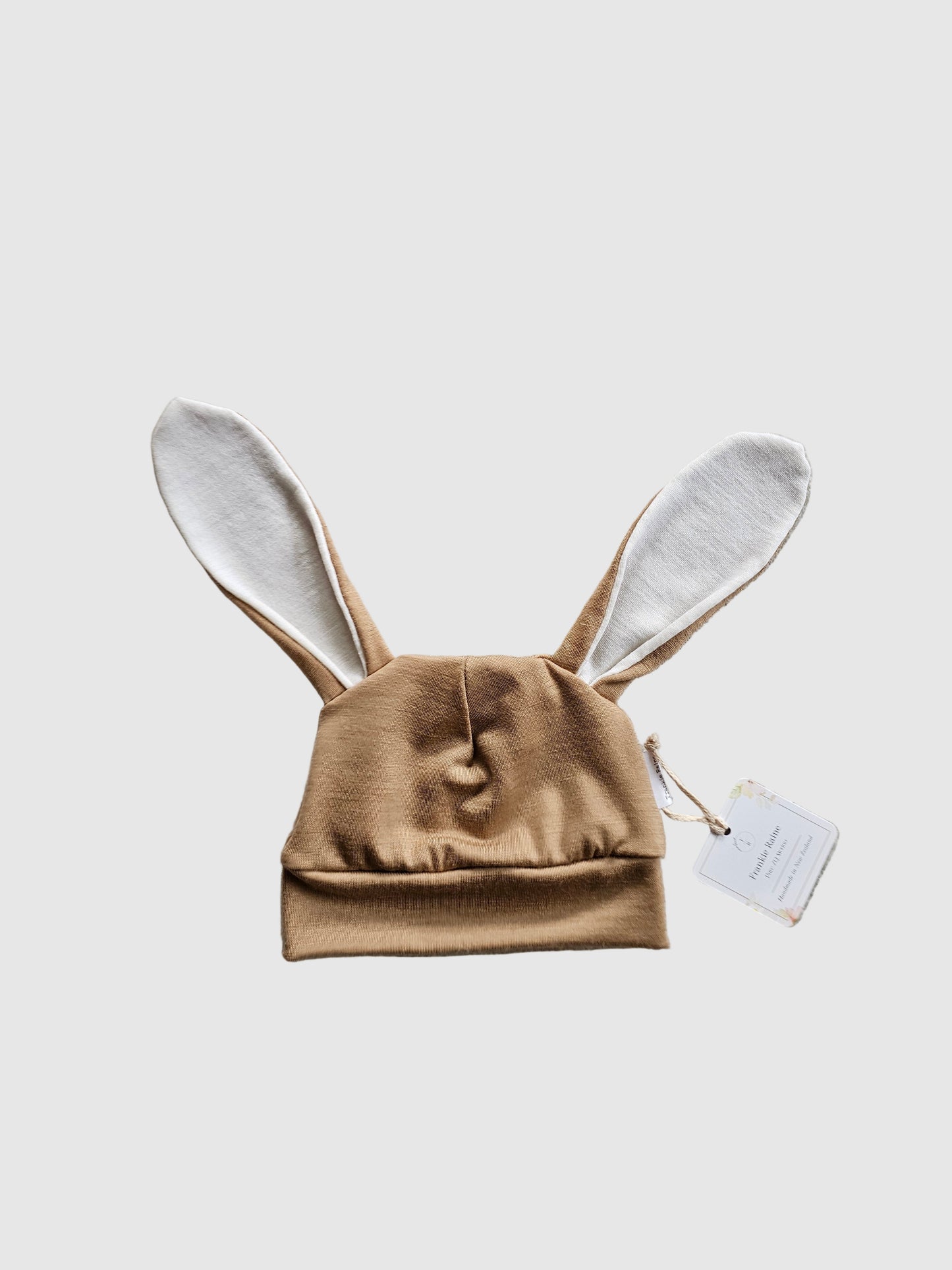 Brown baby outfit with bunny ears on a textured gray surface
