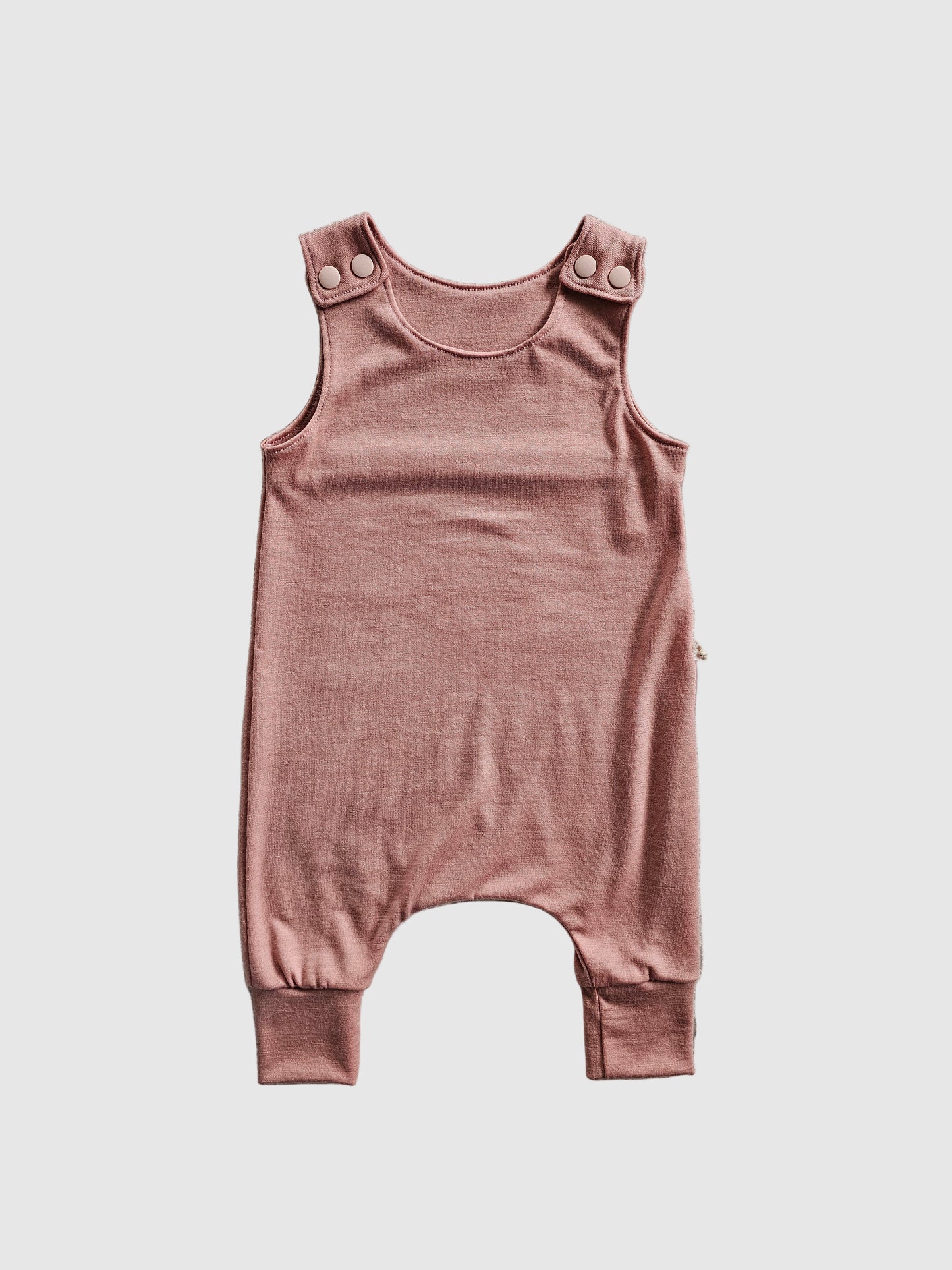 Pink baby romper with a tag on a gray textured background
