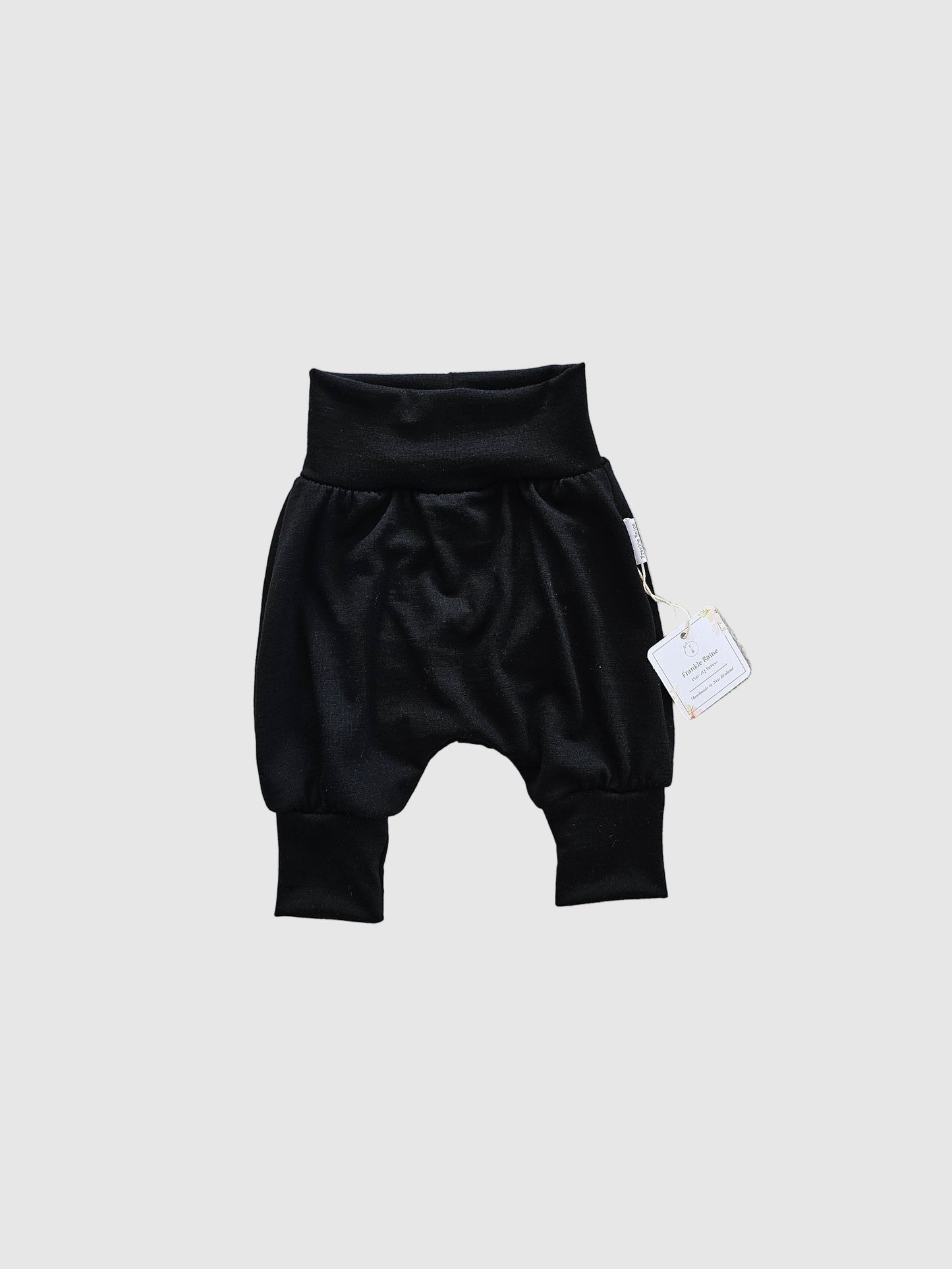 Black baby outfit with a tag on a white surface