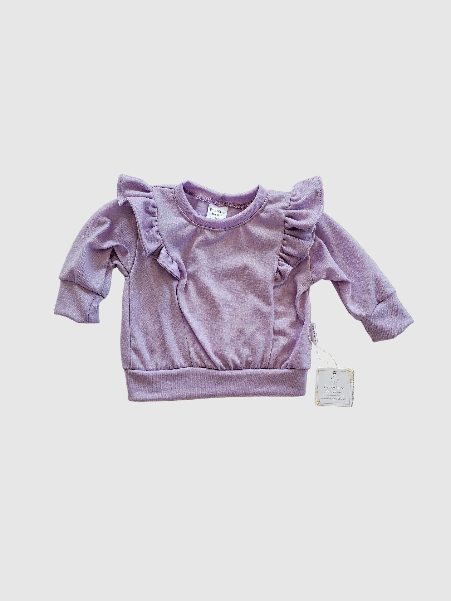 Purple baby outfit with matching headband on a beige surface