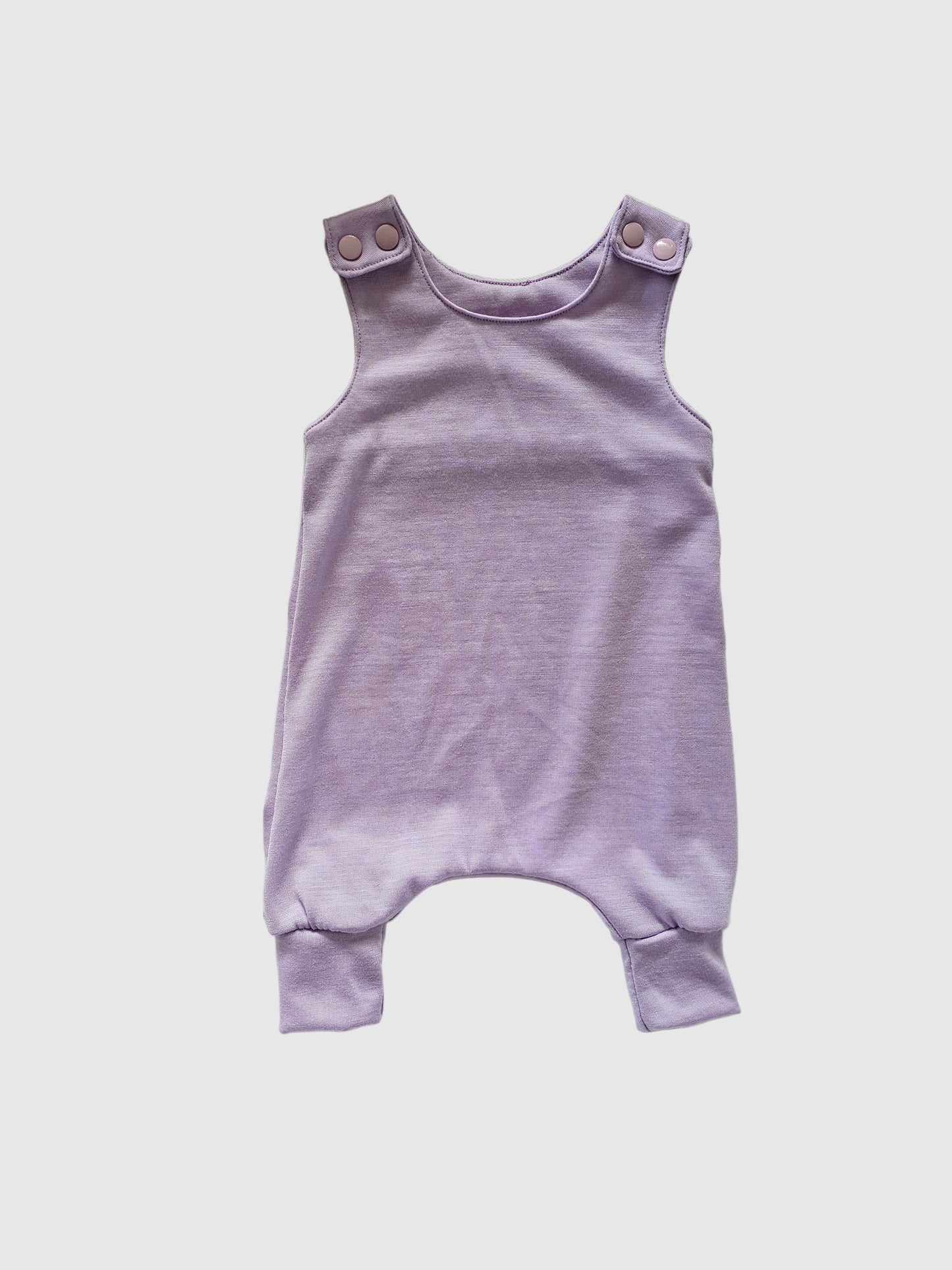 Purple baby romper on a white oval cushion with a brown border.