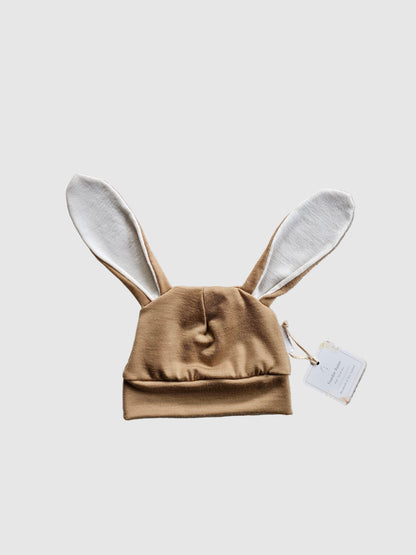 Brown baby outfit with bunny ears on a textured gray surface