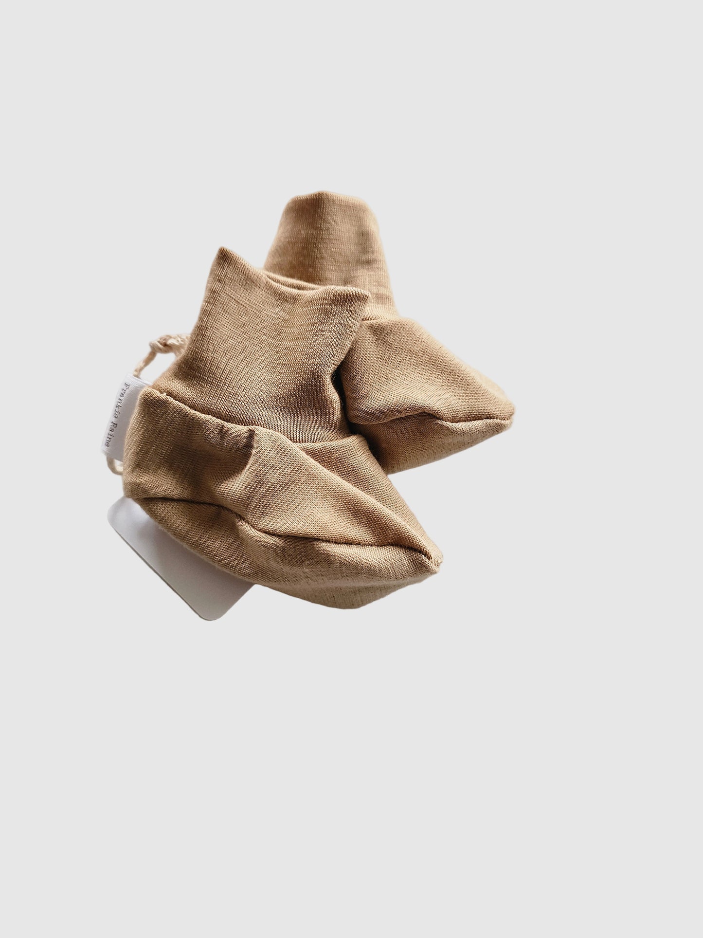 Pair of beige baby socks on a textured white surface