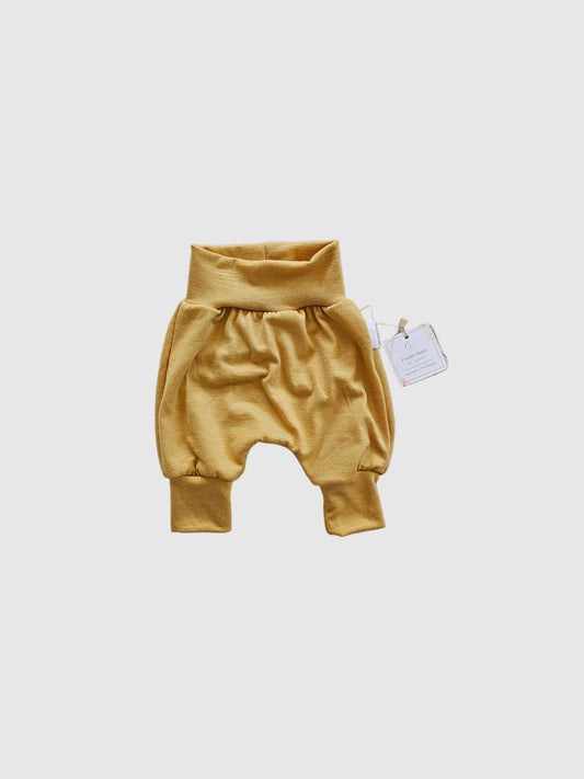 Gold-colored garment on a textured white surface with a visible tag.