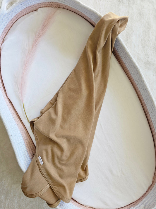 Biscotti merino baby swaddle wrap, styled flat lay on change basket.