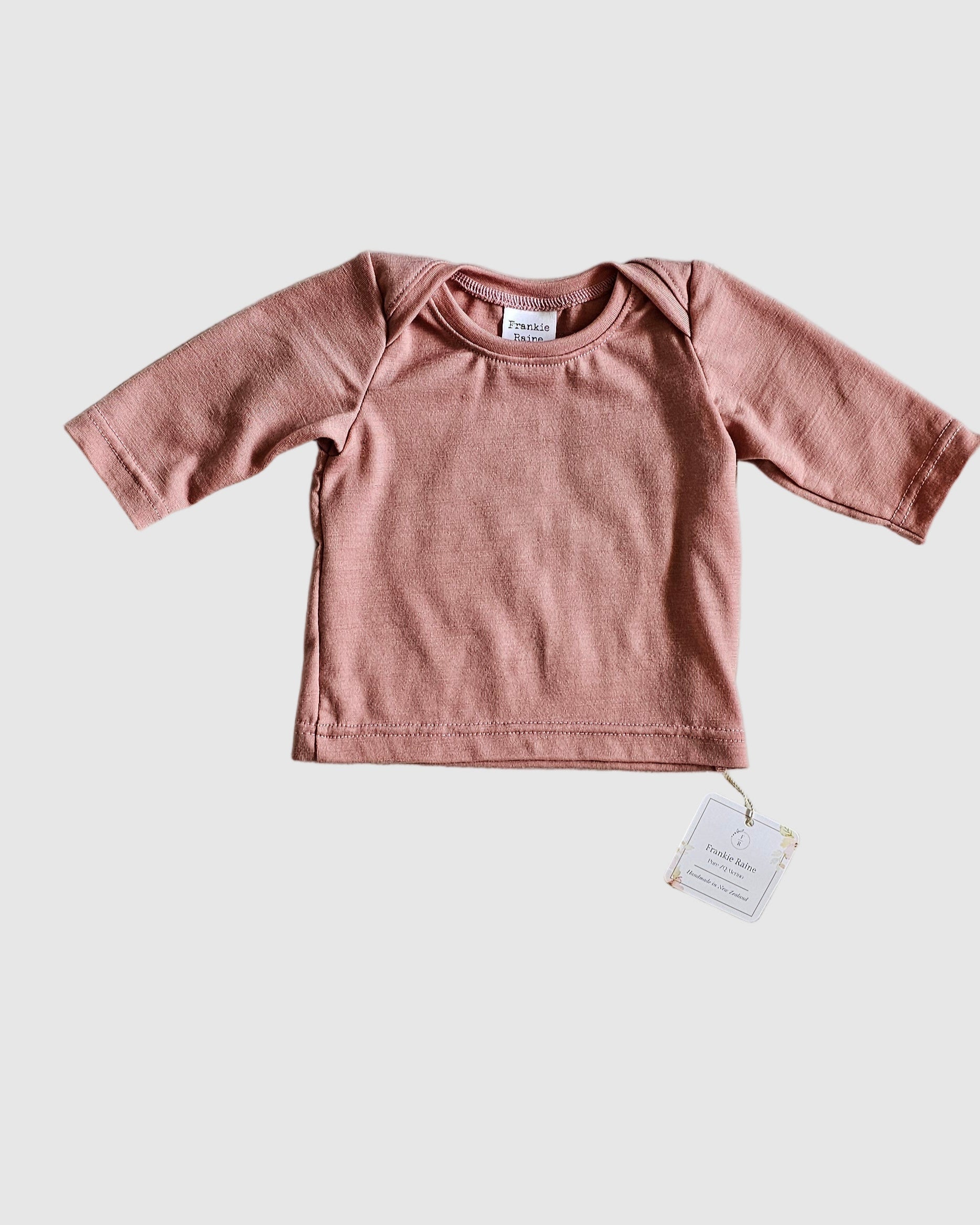 Pink baby outfit with a tag on a gray surface