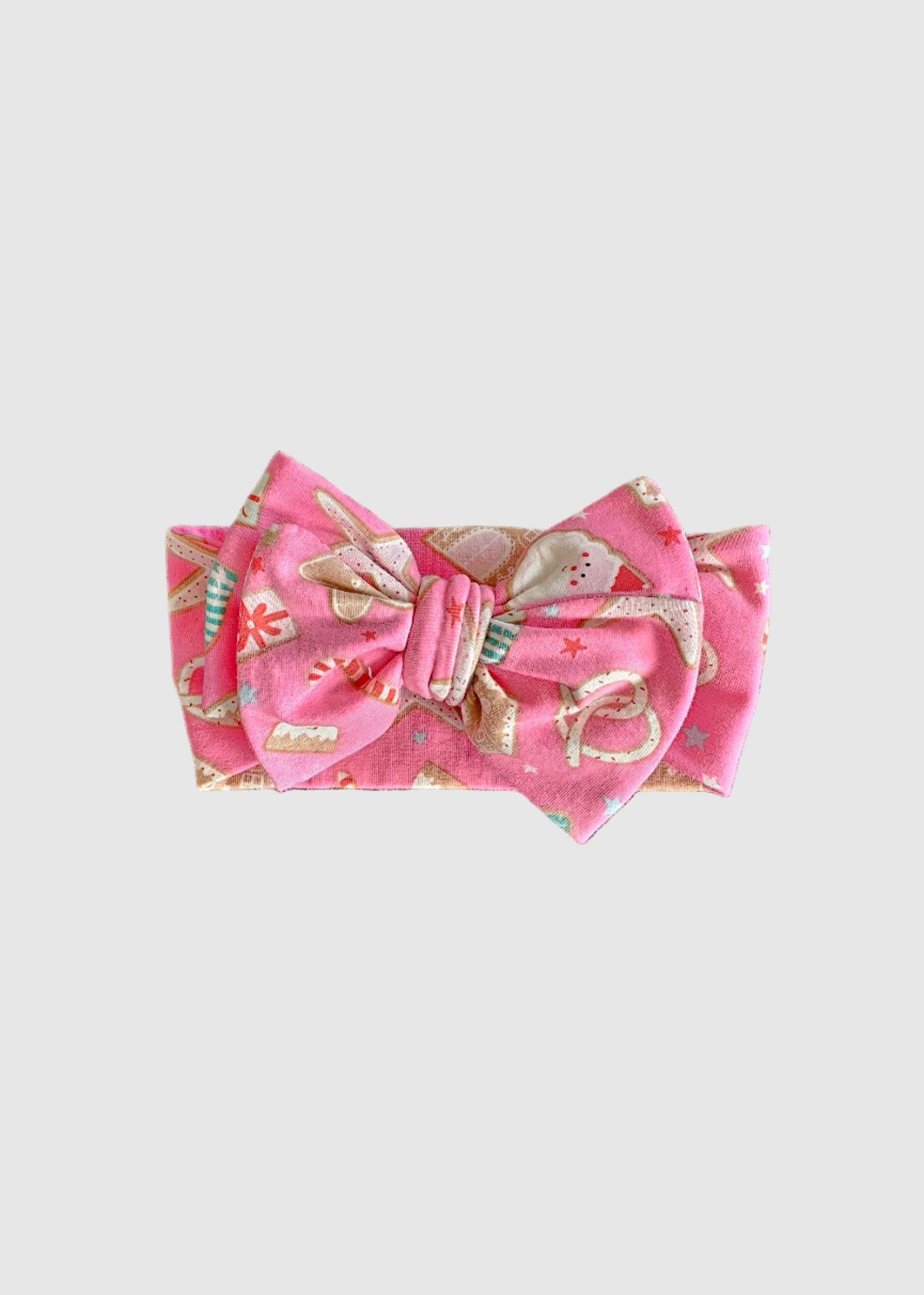 Pink fabric item with a bow on a gray carpet