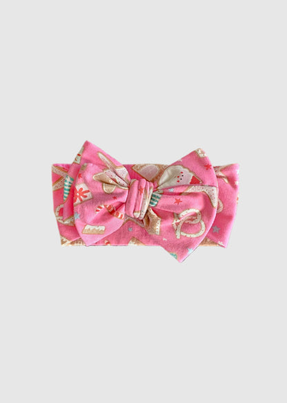 Pink fabric item with a bow on a gray carpet