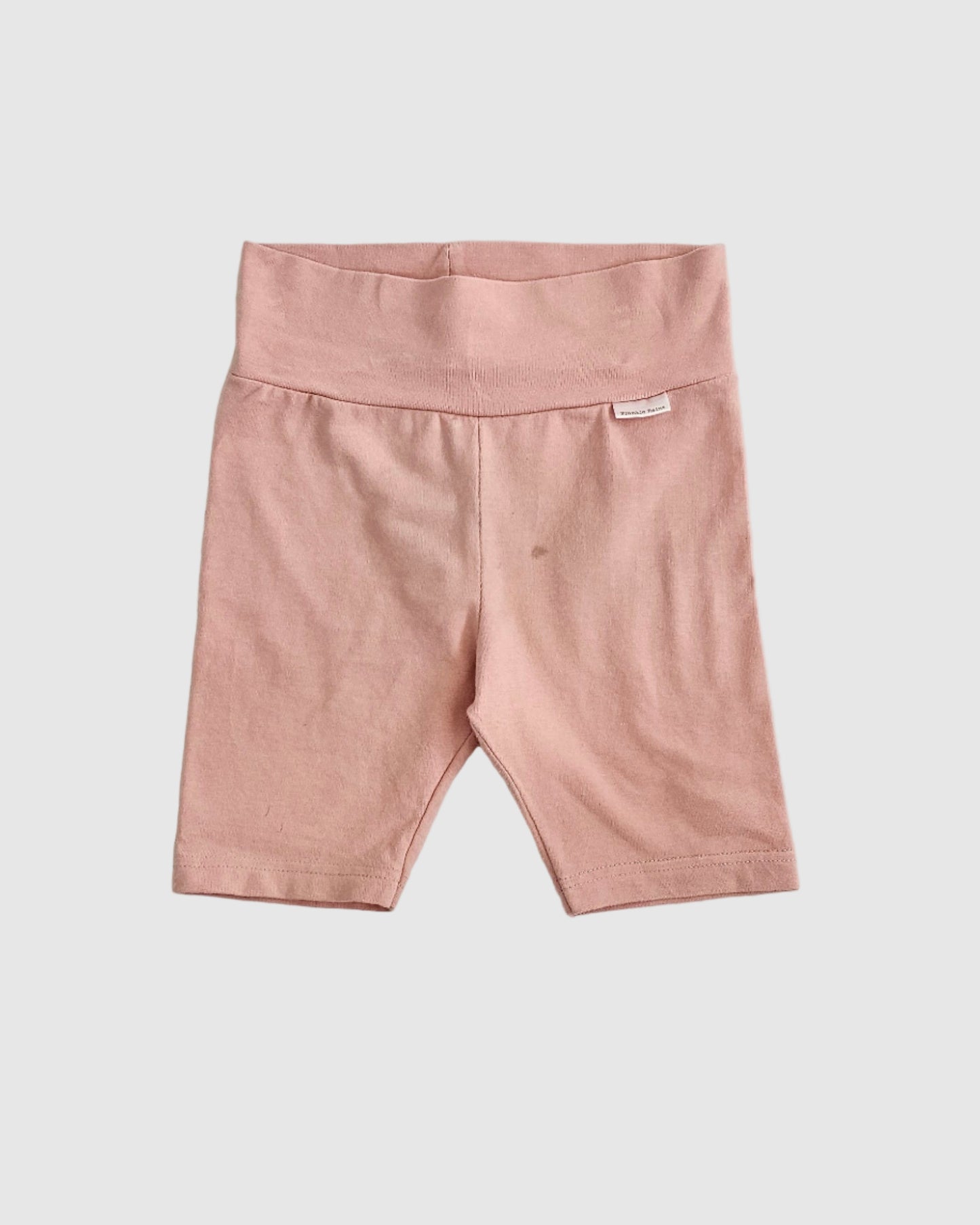 Pink pants on a light gray bedspread