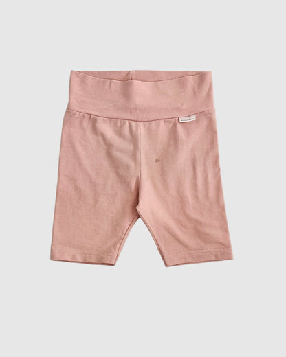 Pink pants on a light gray bedspread