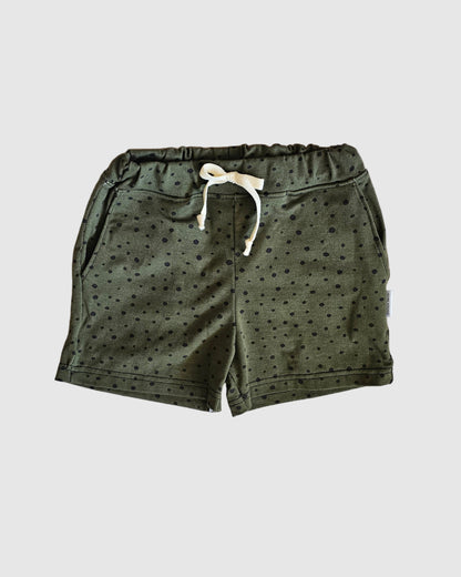 Green shorts with a white drawstring on a checkered fabric background